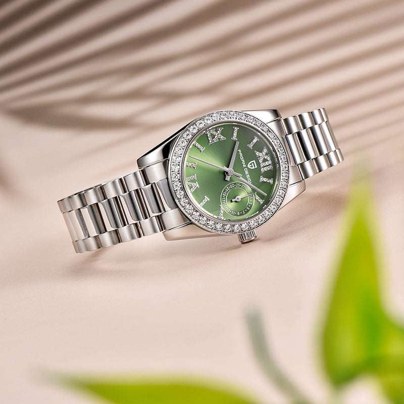 Sage green dial Pagani Design ladies watch on a steel bracelet beside palm leaves